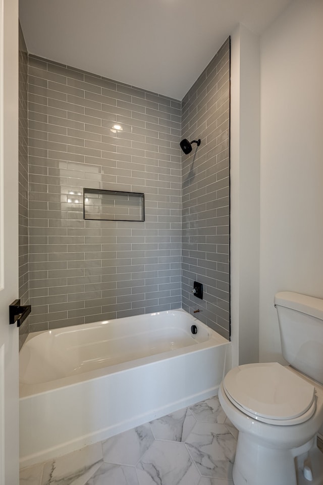 bathroom featuring toilet and tiled shower / bath