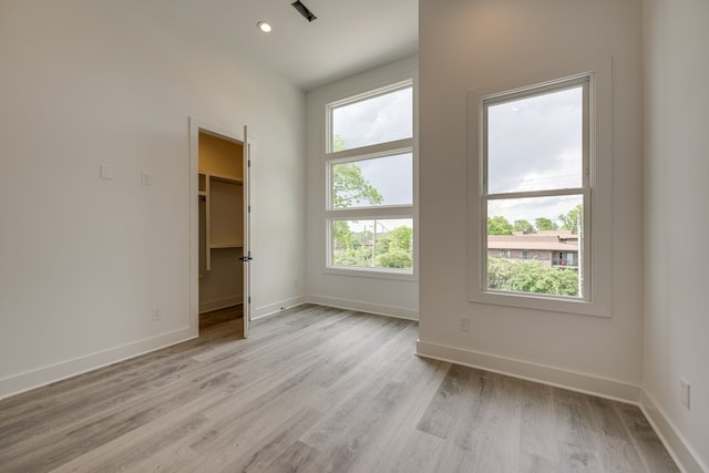 empty room with light hardwood / wood-style floors and plenty of natural light