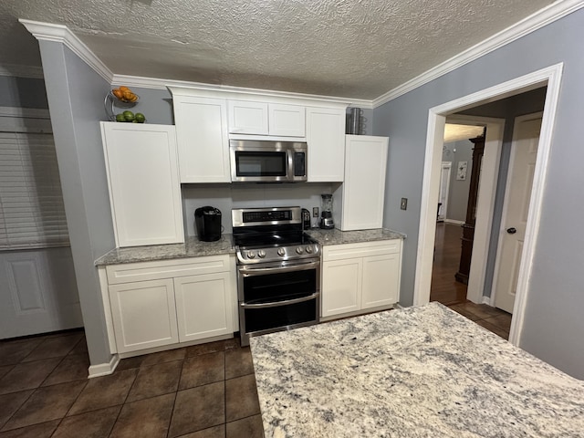 kitchen with white cabinets, appliances with stainless steel finishes, a textured ceiling, ornamental molding, and light stone counters