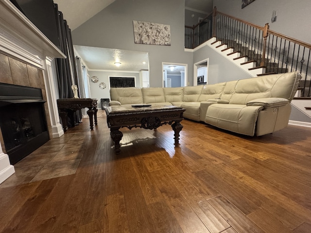 living room featuring a tiled fireplace, wood-type flooring, and high vaulted ceiling