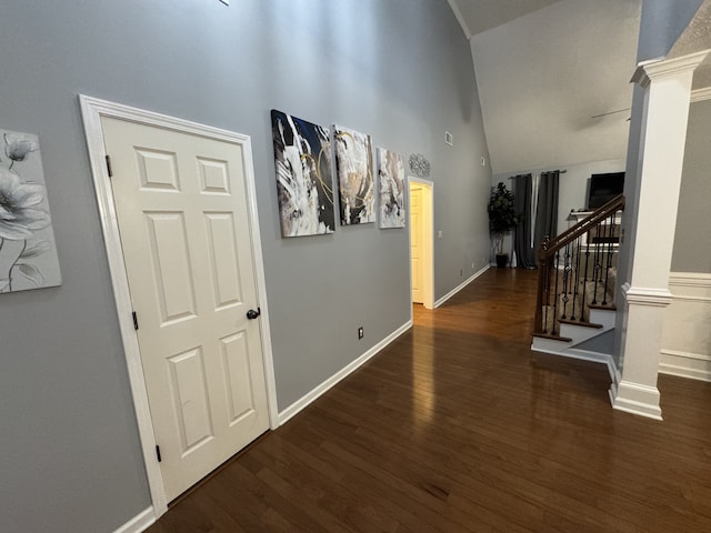 corridor with a towering ceiling, dark wood-type flooring, and decorative columns