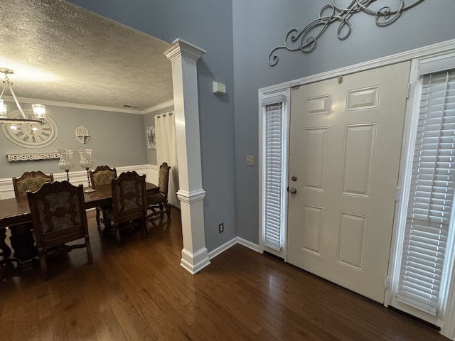 entryway with ornate columns, dark wood-type flooring, crown molding, a notable chandelier, and a textured ceiling