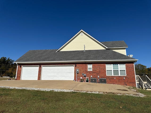 exterior space featuring a garage, a front lawn, and central air condition unit