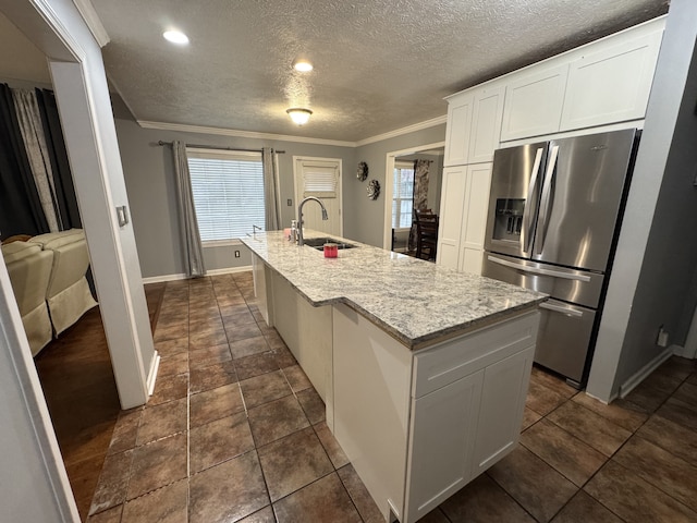 kitchen with white cabinets, an island with sink, stainless steel fridge with ice dispenser, crown molding, and sink