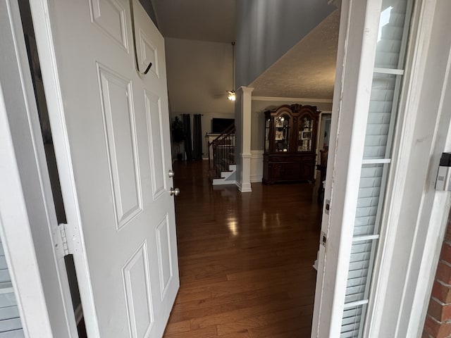 hallway featuring ornate columns, crown molding, and dark hardwood / wood-style floors