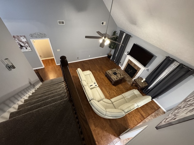 living room featuring a fireplace, dark hardwood / wood-style floors, high vaulted ceiling, and ceiling fan