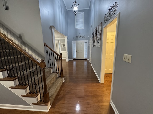 foyer entrance featuring a chandelier, crown molding, dark hardwood / wood-style floors, and a high ceiling