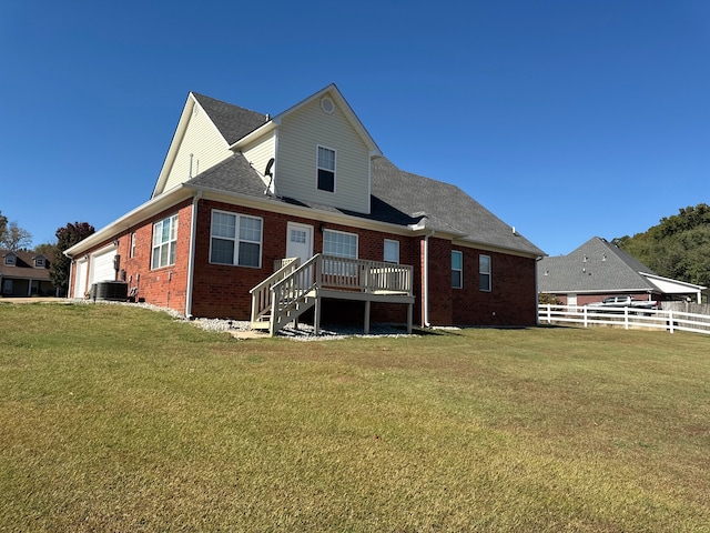 rear view of property with a wooden deck, a yard, cooling unit, and a garage