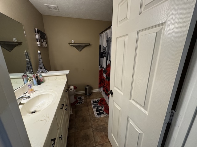 bathroom featuring tile patterned floors, toilet, curtained shower, vanity, and a textured ceiling