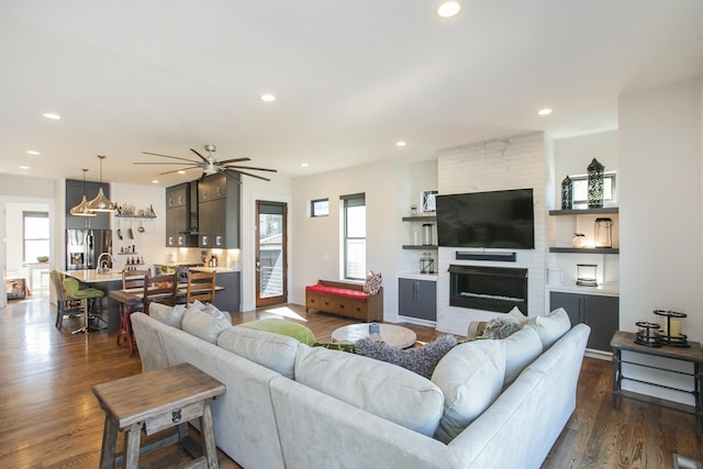 living room with plenty of natural light, ceiling fan, sink, and dark wood-type flooring