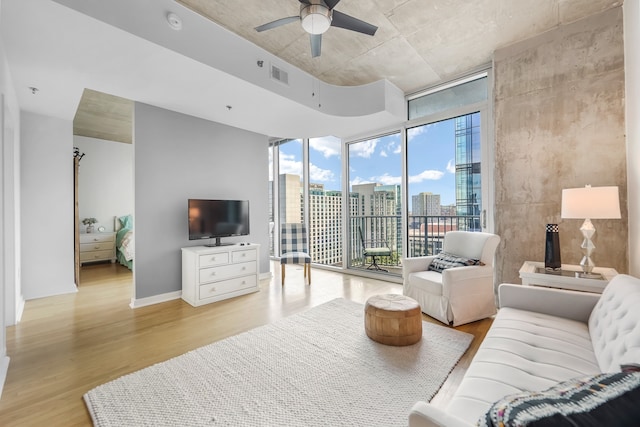 living room featuring ceiling fan, a wall of windows, and light hardwood / wood-style flooring