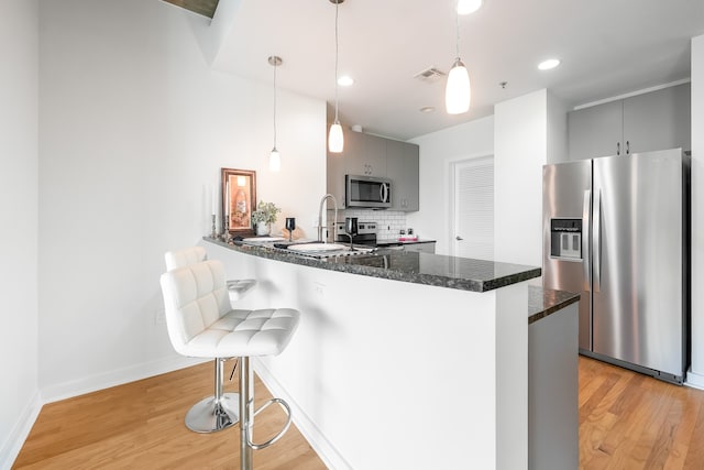 kitchen with appliances with stainless steel finishes, gray cabinets, and hanging light fixtures