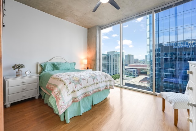 bedroom with access to exterior, light hardwood / wood-style flooring, expansive windows, and ceiling fan