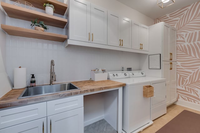 clothes washing area with sink, separate washer and dryer, and cabinets