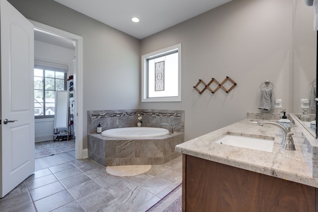 bathroom featuring vanity and tiled bath