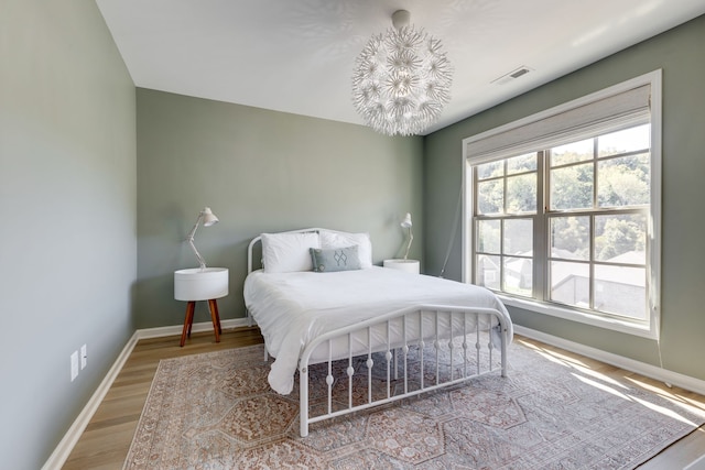 bedroom featuring an inviting chandelier and hardwood / wood-style floors