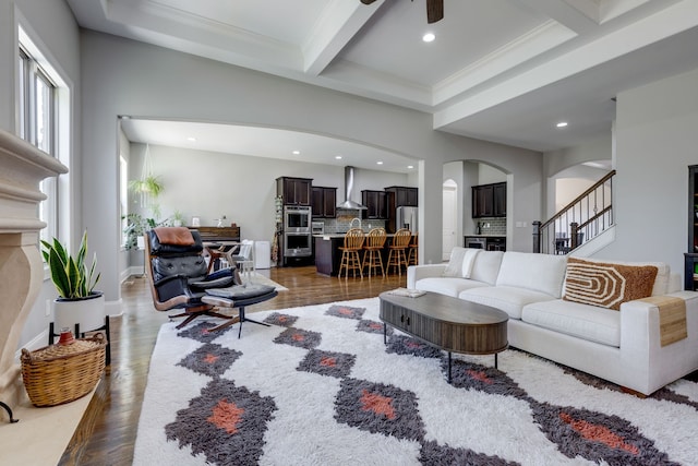 living room with beam ceiling, ornamental molding, ceiling fan, and dark hardwood / wood-style flooring