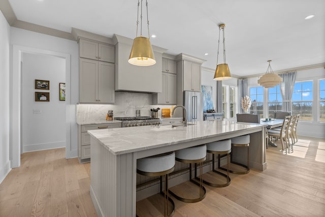 kitchen with gray cabinets, stainless steel appliances, pendant lighting, and light hardwood / wood-style floors