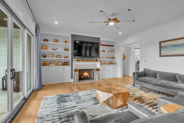 living room featuring light hardwood / wood-style flooring, ornamental molding, ceiling fan, and a wealth of natural light