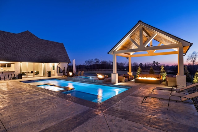 pool at dusk with a gazebo, a patio area, and an in ground hot tub