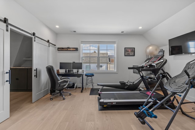 exercise room with vaulted ceiling and light hardwood / wood-style floors