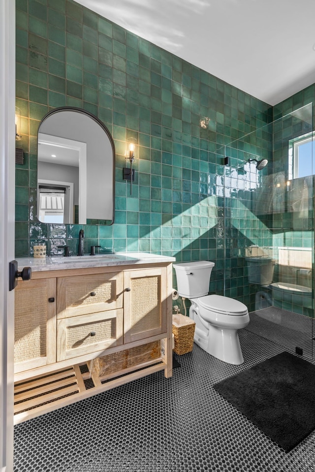 bathroom featuring tile patterned floors, toilet, vanity, a shower, and tile walls