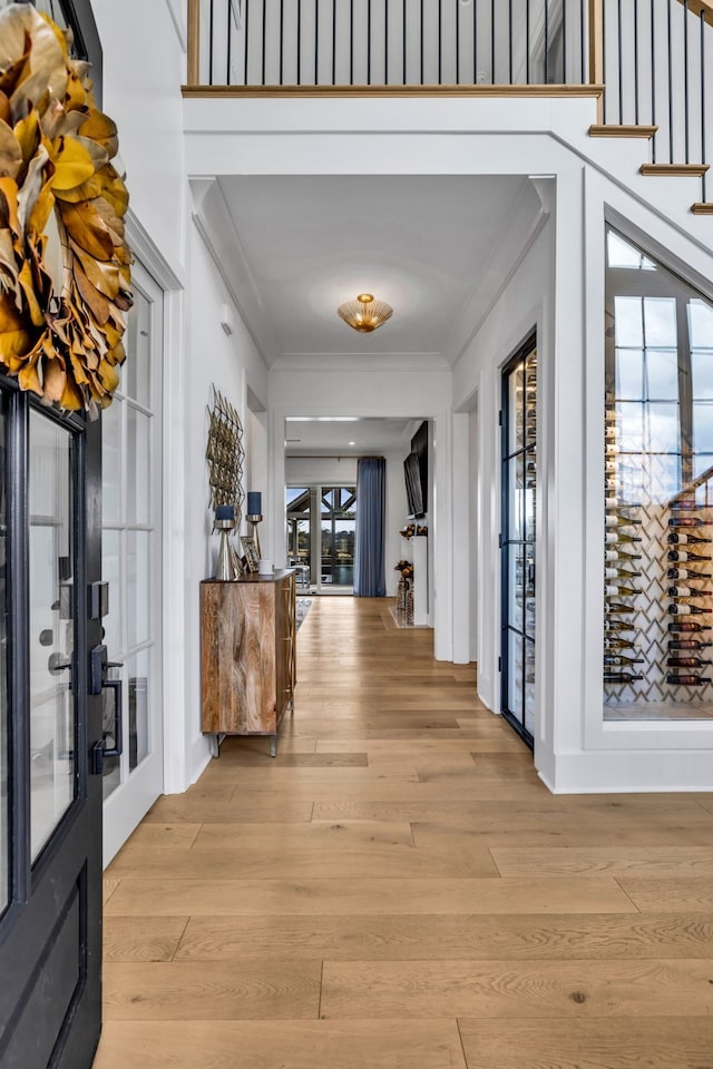 corridor featuring ornamental molding and light hardwood / wood-style flooring