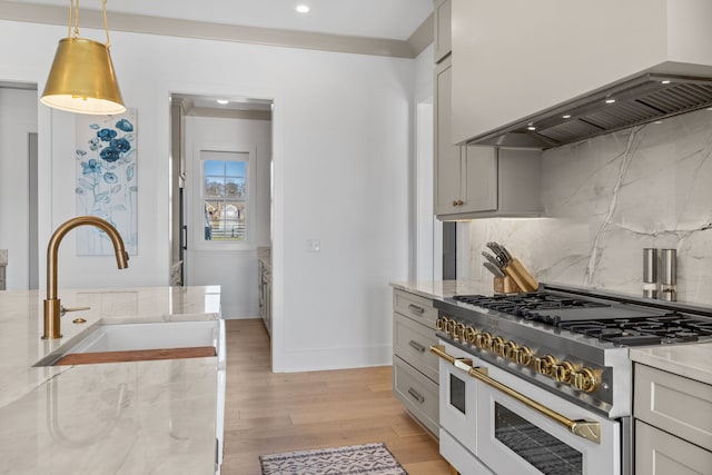 kitchen with light hardwood / wood-style flooring, custom range hood, range with two ovens, pendant lighting, and sink