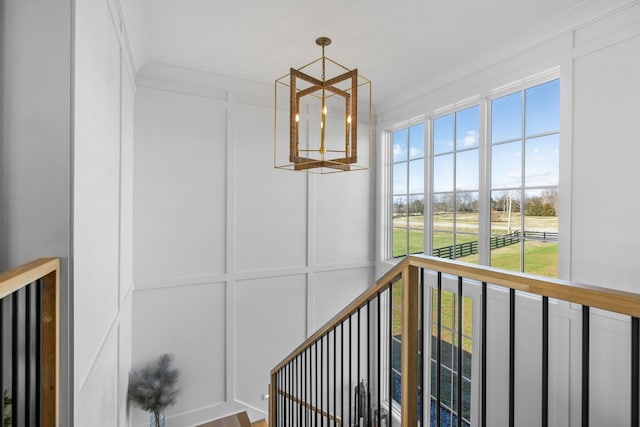 staircase with ornamental molding, wood-type flooring, and an inviting chandelier