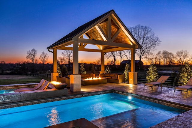 pool at dusk with a patio and a gazebo