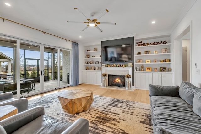 living room with french doors, light hardwood / wood-style flooring, ornamental molding, built in features, and ceiling fan