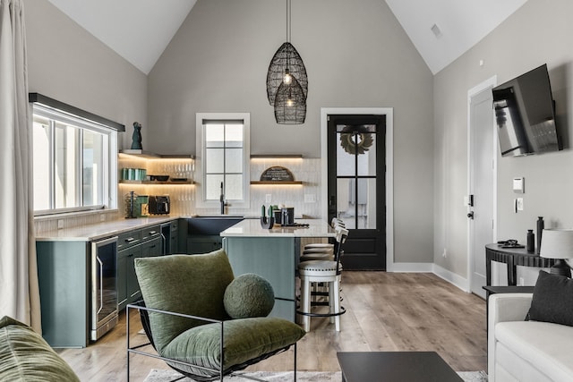 living room with light hardwood / wood-style floors, high vaulted ceiling, a healthy amount of sunlight, and beverage cooler