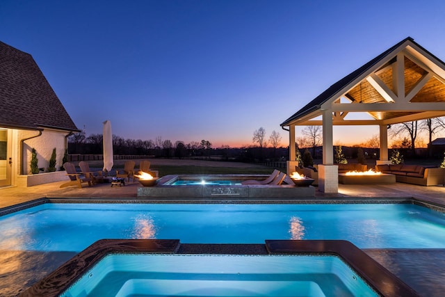 pool at dusk with a gazebo, an in ground hot tub, and a patio