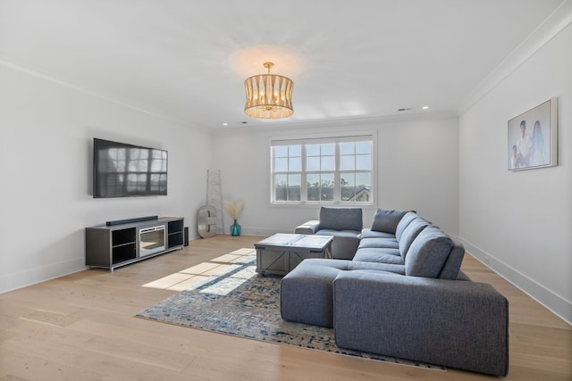 living room featuring ornamental molding, a notable chandelier, and light wood-type flooring