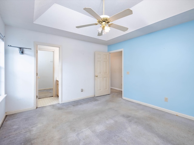 unfurnished bedroom featuring ensuite bathroom, light colored carpet, and ceiling fan