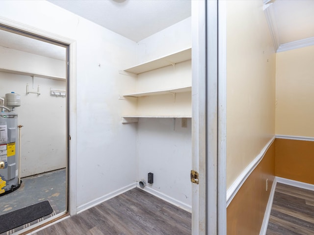 laundry area featuring water heater, dark hardwood / wood-style floors, and crown molding