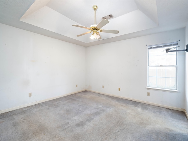 carpeted spare room featuring a tray ceiling and ceiling fan