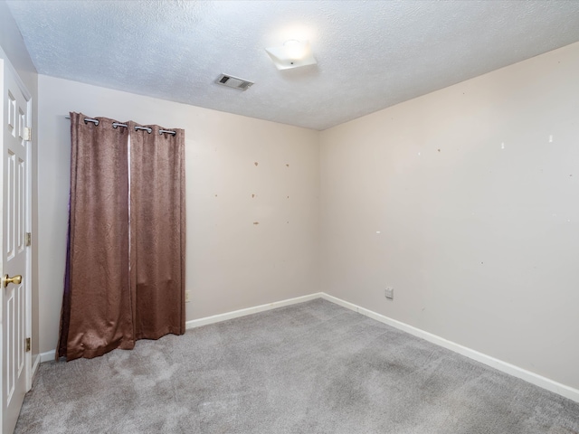 empty room with light carpet and a textured ceiling