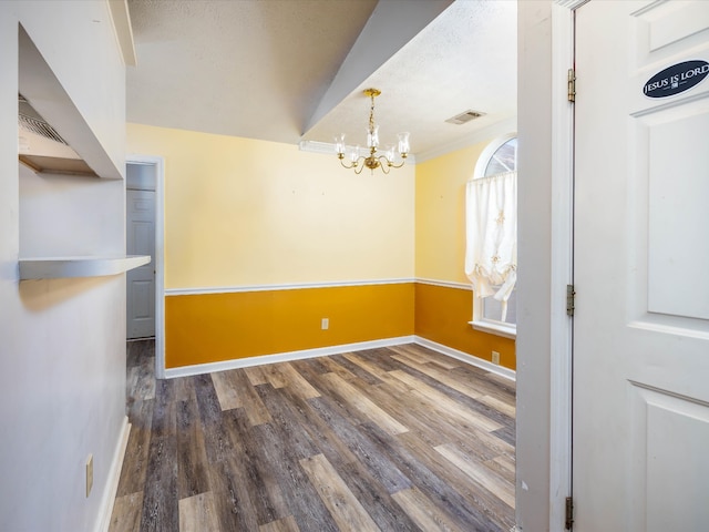 unfurnished dining area with lofted ceiling, dark wood-type flooring, a textured ceiling, and a chandelier