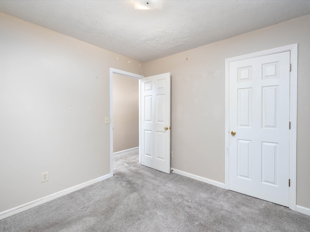 unfurnished room featuring light carpet and a textured ceiling