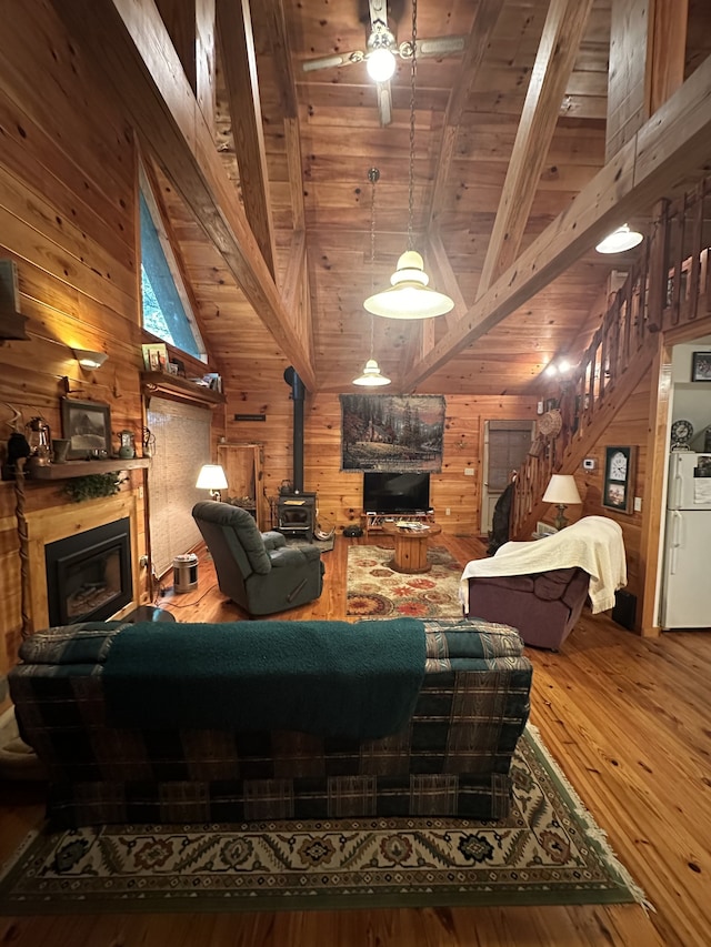 living room with hardwood / wood-style flooring, wooden ceiling, wooden walls, and lofted ceiling with beams