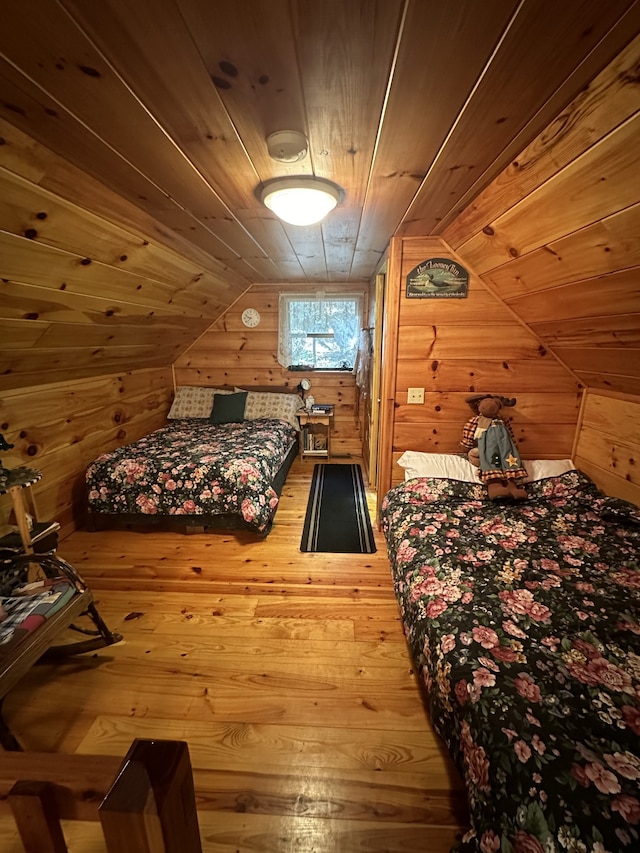 bedroom with wooden walls, vaulted ceiling, hardwood / wood-style flooring, and wooden ceiling