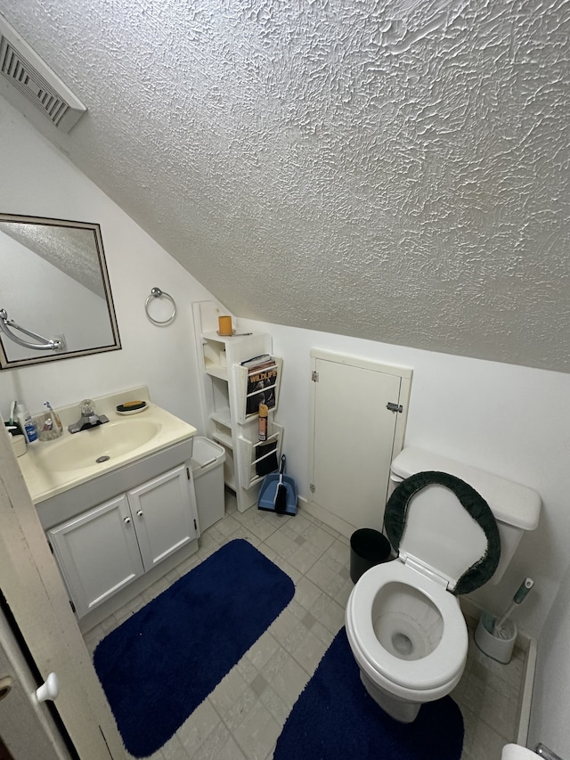 bathroom featuring vanity, a textured ceiling, and toilet