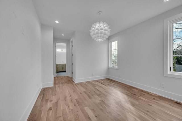 unfurnished dining area featuring an inviting chandelier and light hardwood / wood-style floors