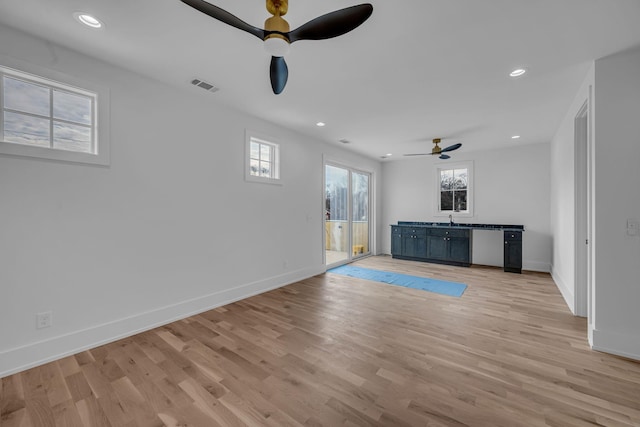 unfurnished living room featuring ceiling fan, sink, and light hardwood / wood-style flooring