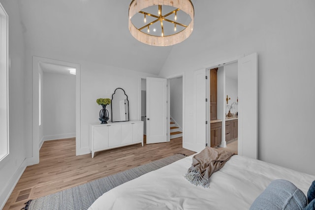 bedroom featuring an inviting chandelier, high vaulted ceiling, connected bathroom, and light hardwood / wood-style floors