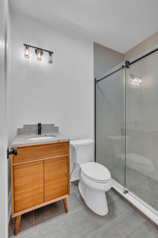 bathroom featuring tile patterned floors, vanity, toilet, and a tile shower