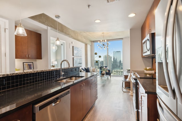 kitchen featuring appliances with stainless steel finishes, an inviting chandelier, light wood-type flooring, pendant lighting, and sink