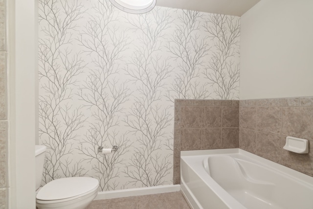 bathroom with tile patterned floors, a tub, and toilet