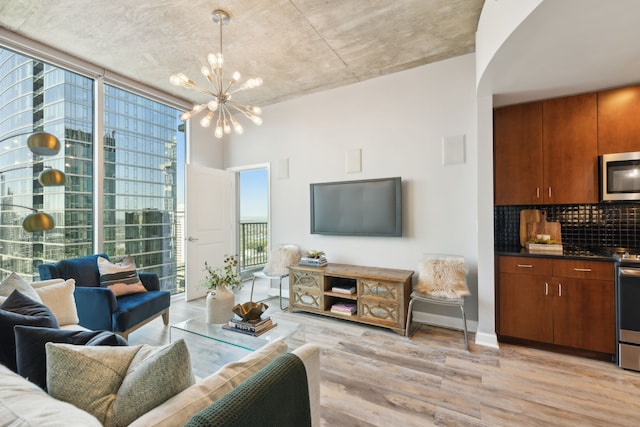 living room with expansive windows, a chandelier, and light wood-type flooring